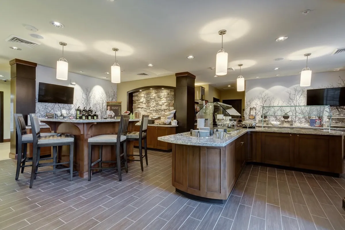 A modern, central bar area with a stone accent wall and a food display counter set the stage for buffet service or relaxed meals. Comfortable seating and a welcoming ambiance encourage both social gatherings and casual dining.